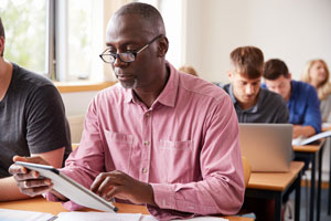 Student Using Digital Tablet In Adult Education Class