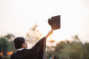 college graduate holding up cap