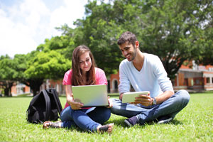 students using mobile devices on campus lawn