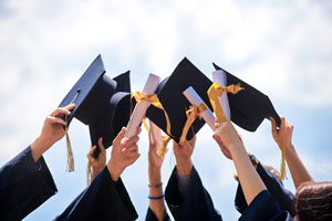 college graduates holding caps up in the air