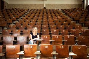 female student sitting alone in large lecture hall