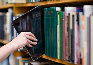 hand pulling tablet off bookshelf of books