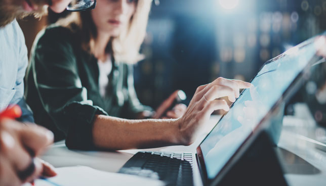 closeup of two coworkers tapping a computer screen