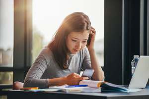 female college student studying with smart phone and laptop