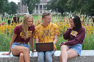 University of Minnesota students using a laptop outdoors