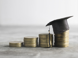 graduation cap sitting on stacks of coins