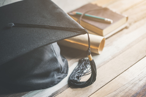 graduation cap and degree on wood table