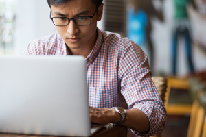 college student concentrating, typing on laptop