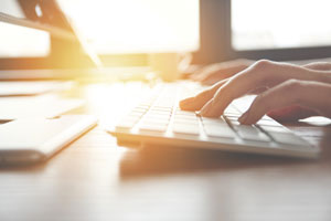 closeup of hands typing on computer keyboard