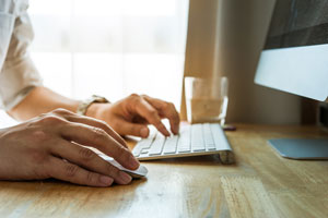 closeup of hands typing at desktop computer