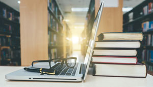 laptop with stack of textbooks