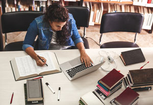 student studying in library with laptop