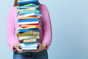 student carrying stack of textbooks