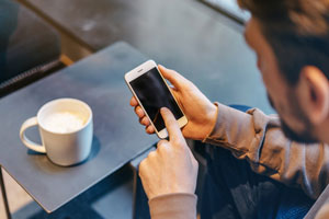 man using mobile phone in cafe