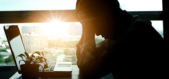 silhouette of stressed woman sitting at laptop