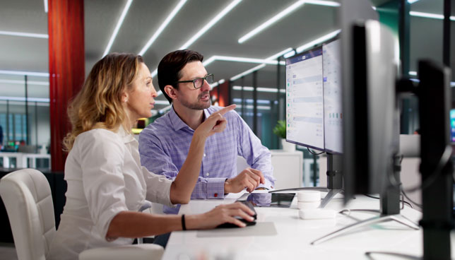 man and woman analyzing data on computer screen