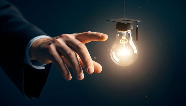 Businessman reaching for glowing lightbulb with a graduation cap