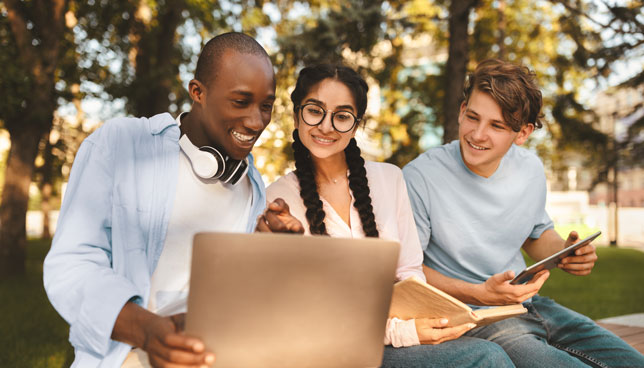 college students studying with laptop in a park
