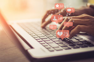closeup of hands on laptop with social media icons