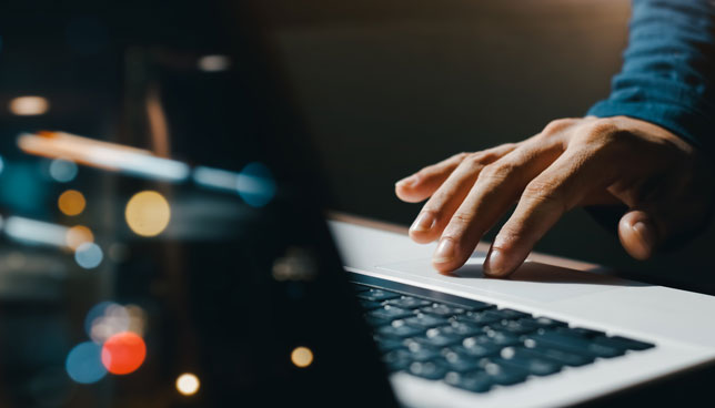 young man hand working on a laptop, bokeh blurred at night 